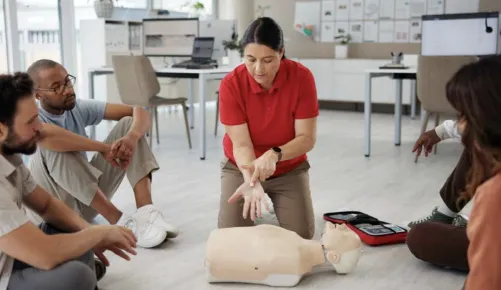 An instructor demonstrates hands-only CPR techniques on a dummy
