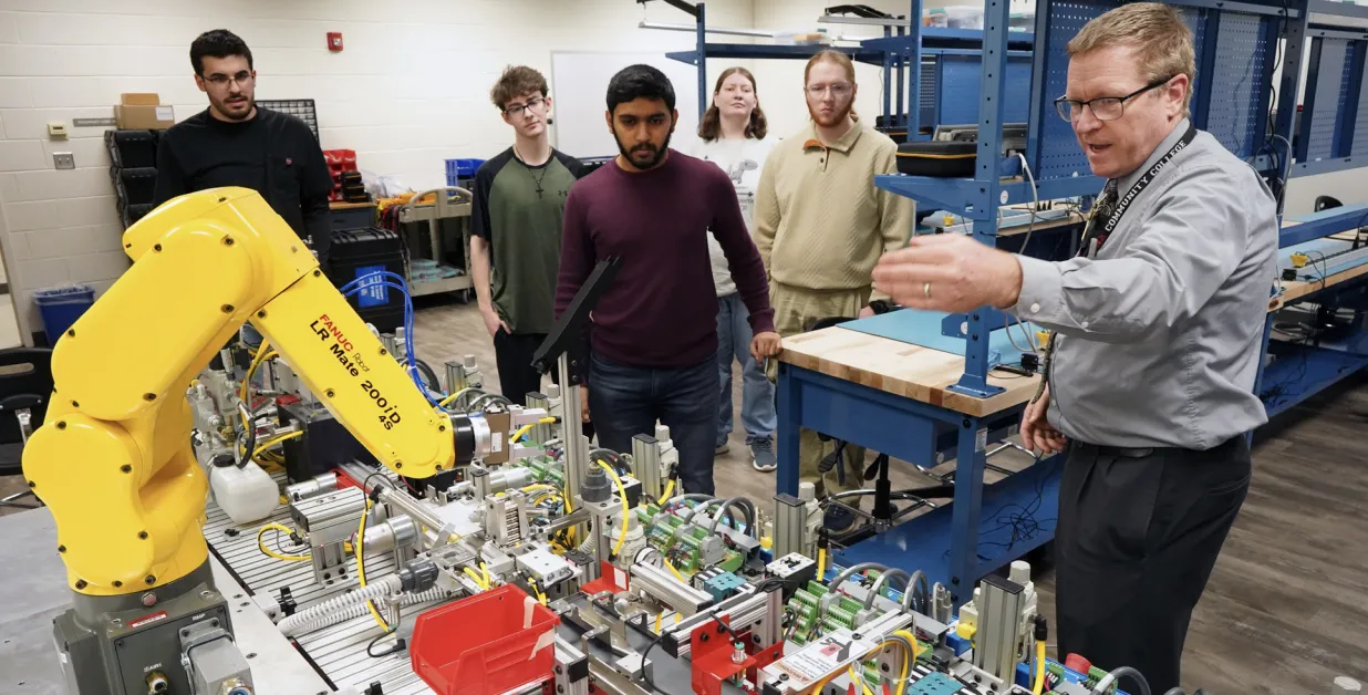 A professor demos a robot to student in a mechatronics lab