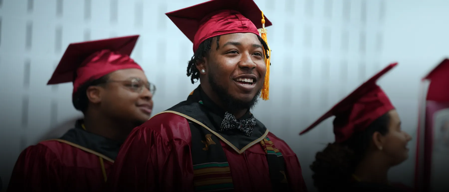 A young man in a cap and gown attending a commencement ceremony