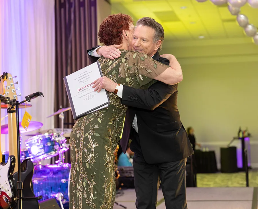 Dr. Gullickson (left) shown embracing Virginia Community College System Chancellor Dr. David Doré after he shared his remarks [Credit: Bryant Cox]
