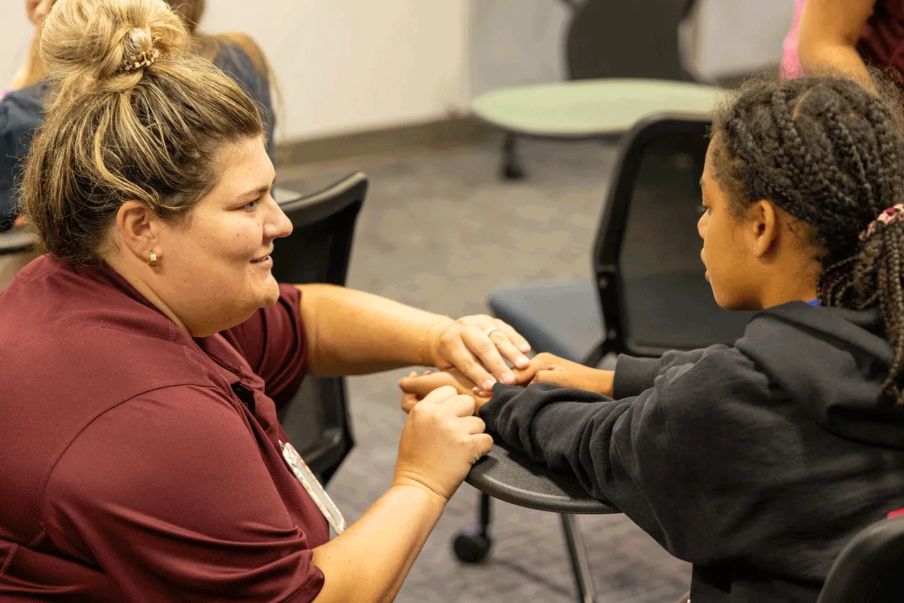 A nursing student (left) showing a participant how to check a pulse