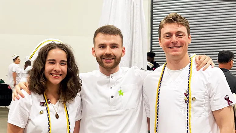 Three nursing graduates, one female and two male, poses together for a photo