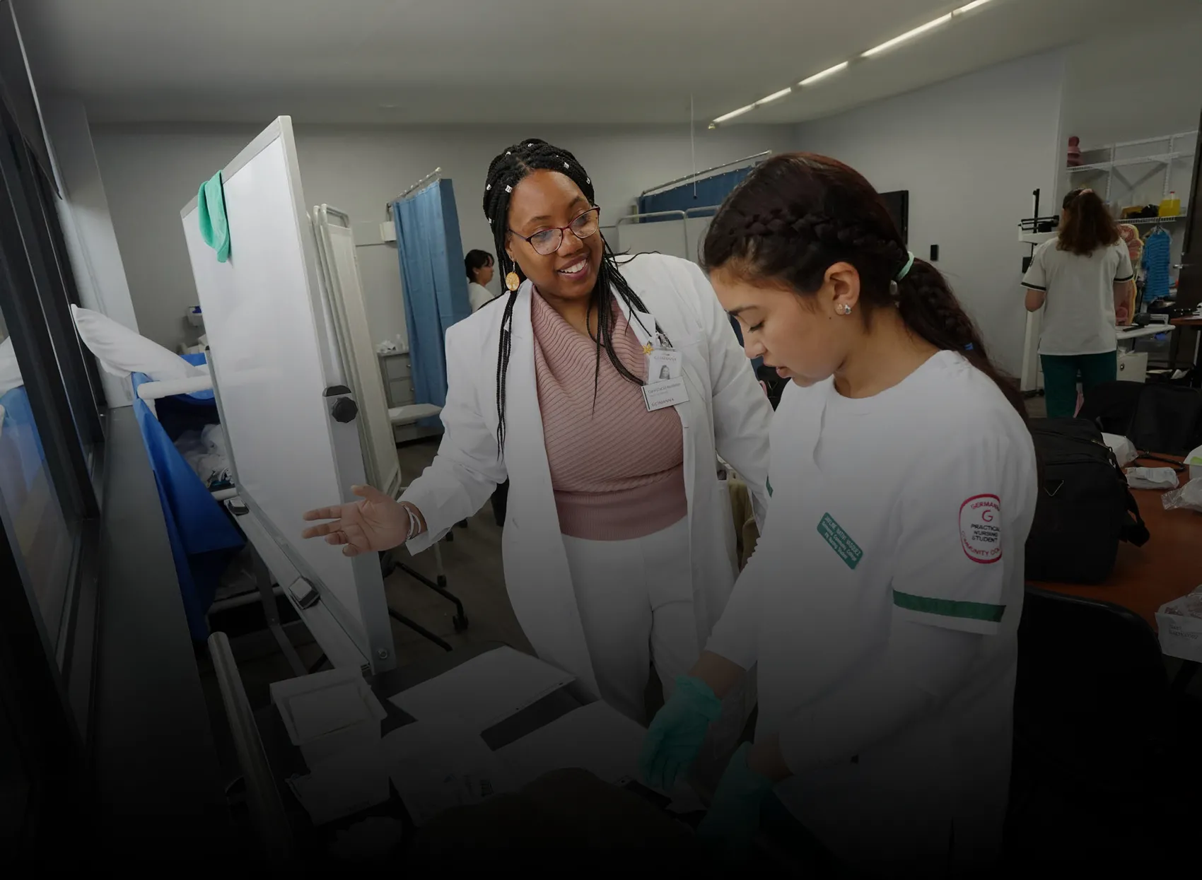 A nursing faculty member guides a student working in a lab