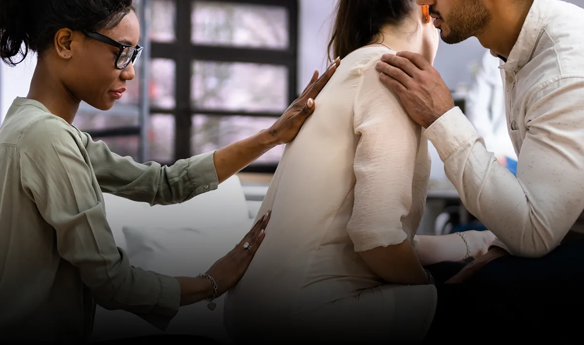 A doula massages the back of a pregnant patient