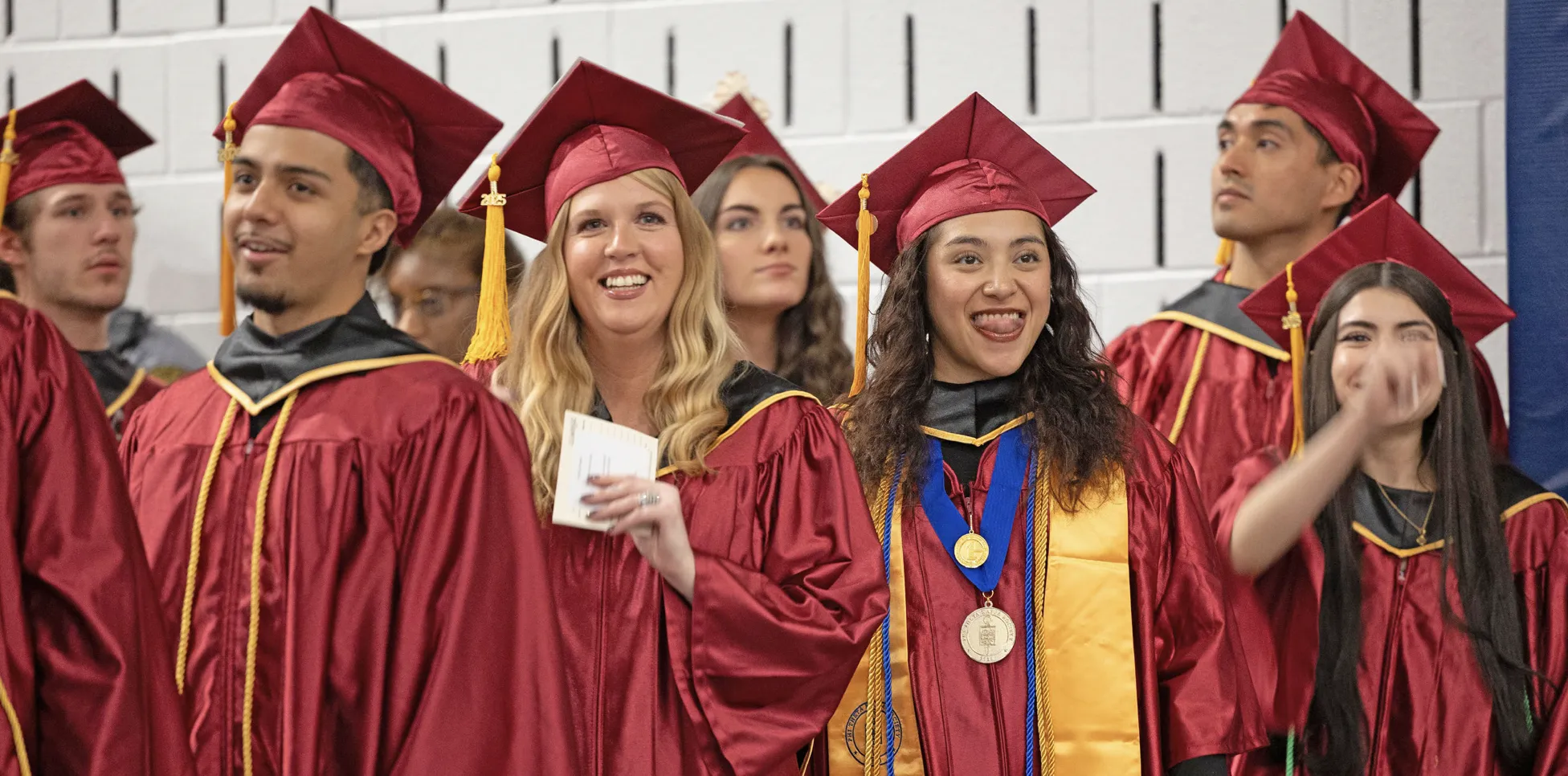 Smiling graduates wearing commencement gowns lining up for the Commencement procession