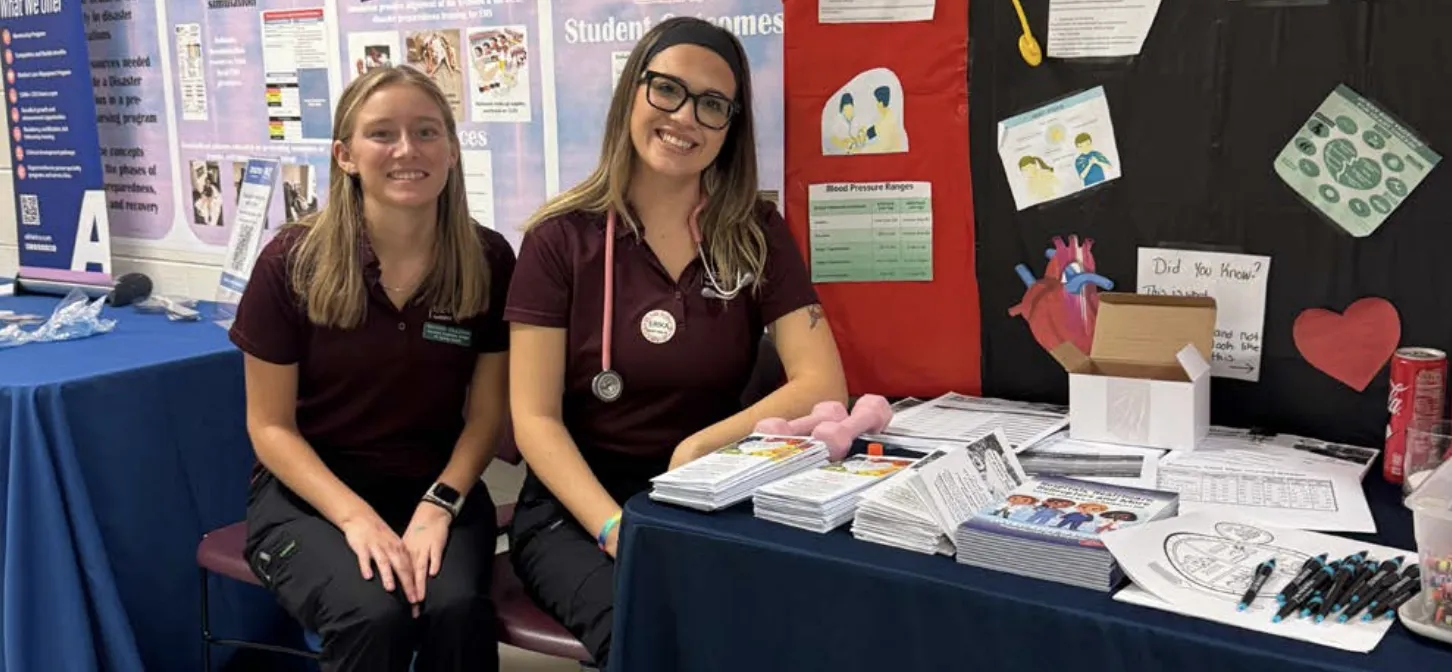 Two Germanna Health Sciences students greet attendees at an open house table