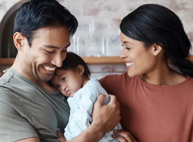 A smiling new father and mother bond over their new baby