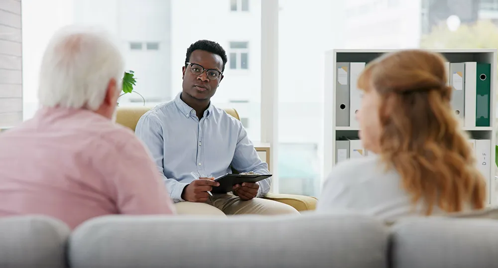 A licensed counselor listens to two patients speaking in an office