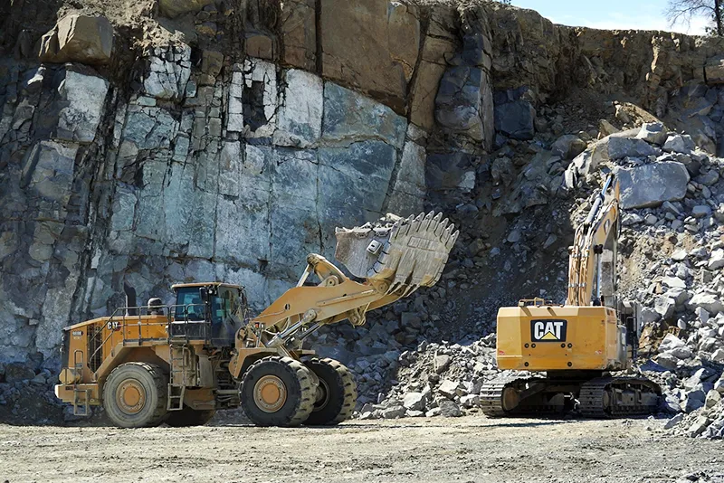 Heavy equipment vehicles move broken rock at Cedar Mountain Stone's quarry