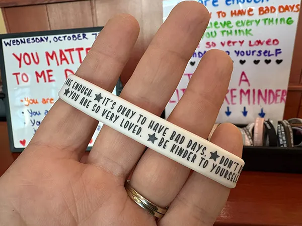 A bracelet with an inspirational message. "It's okay to have bad days. You are so very loved. Be kinder to yourself."