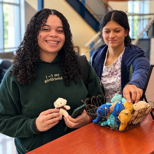 Students pose with a tiny teddy bear during National Bring Your Teddy Bear to School Day