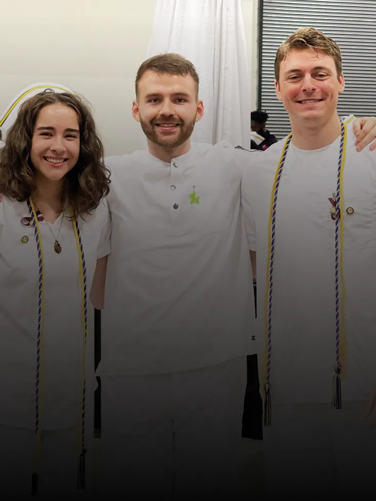 Three young nursing graduates in uniform smile at the camera