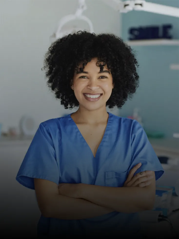 A smiling dental assistant awaits the next patient in the exam room