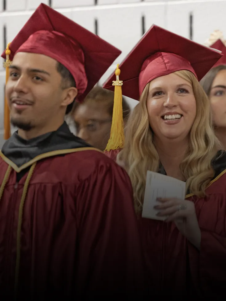College graduates in caps and gowns line up for a Commencement procession