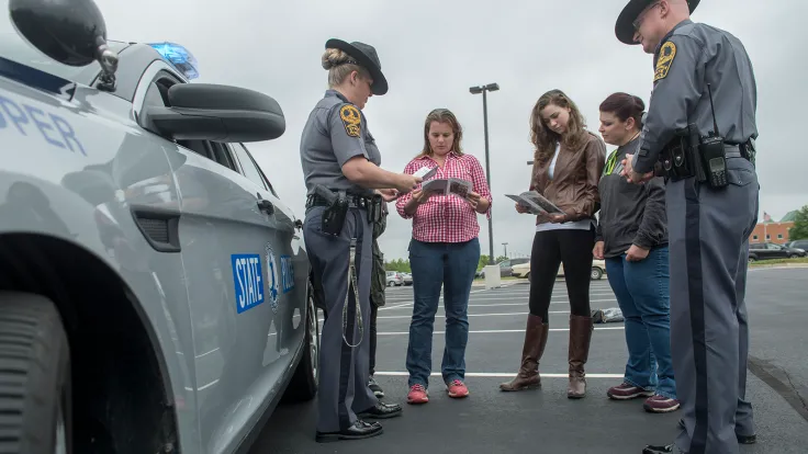 Two Administration of Justice students working in the field with two state police officers