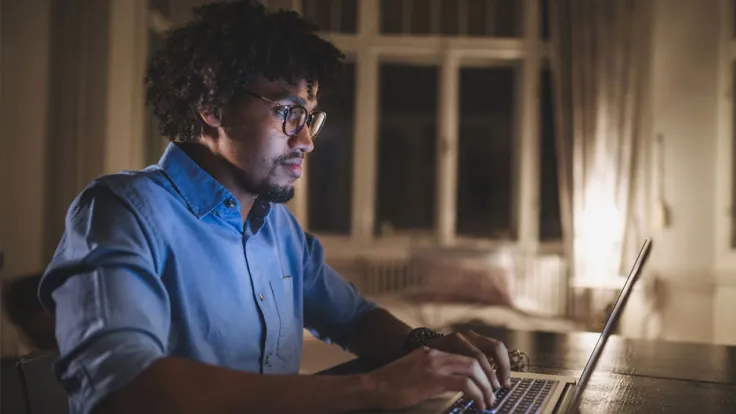 IT professional working at his desk using a laptop computer