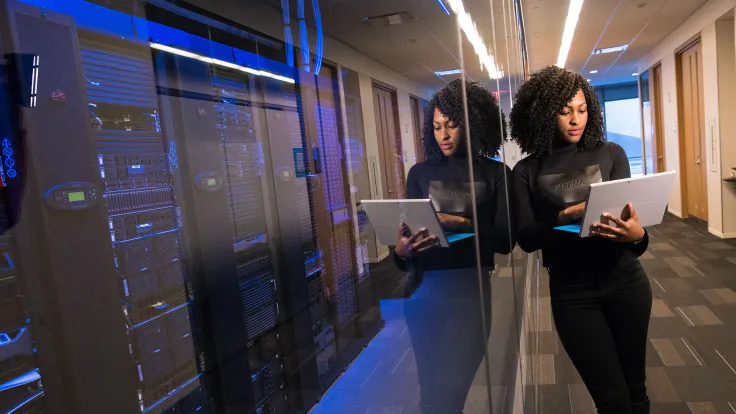 Woman in black working on computer in server room