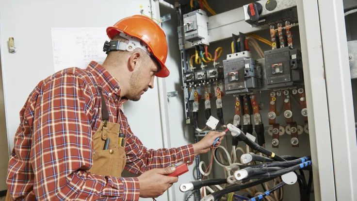 Electrician working in front of fuse box