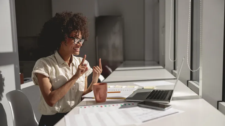 Happy lady learning and communicating in sign language online while sitting in the office