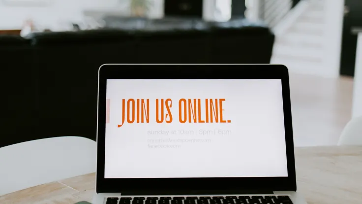 Laptop computer sitting on desk with a message saying to Join Us Online