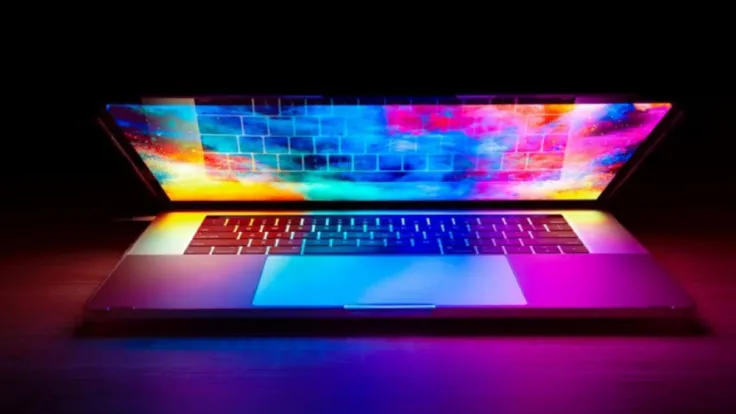 laptop computer half open on desk with rainbow of colors displayed