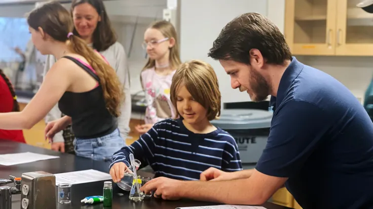 An adult and a child using a flask in a chemistry lab