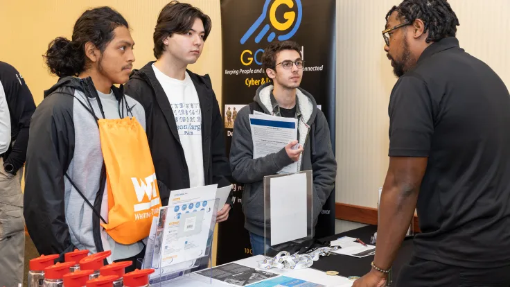Students speak to a vendor at a career fair