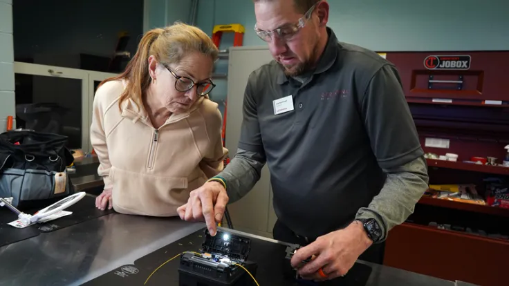 A student watches a demo from a fiber optics installation instructor