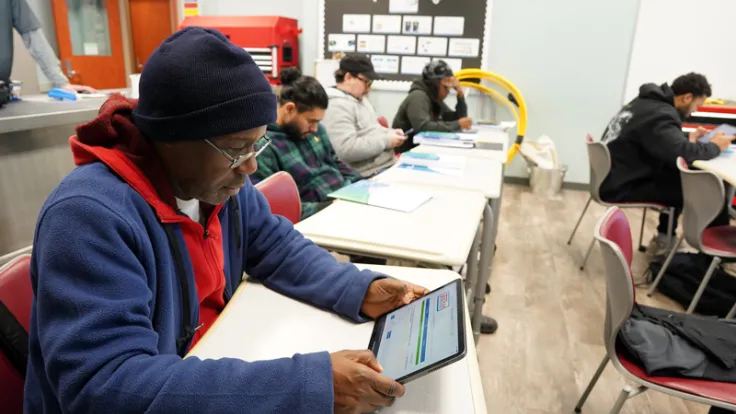 A student reads fiber optics installer course training materials in the classroom