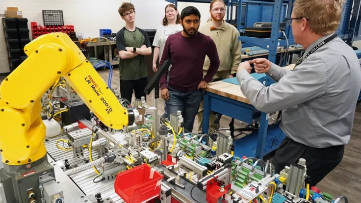 A professor demonstrates a robot to watching students
