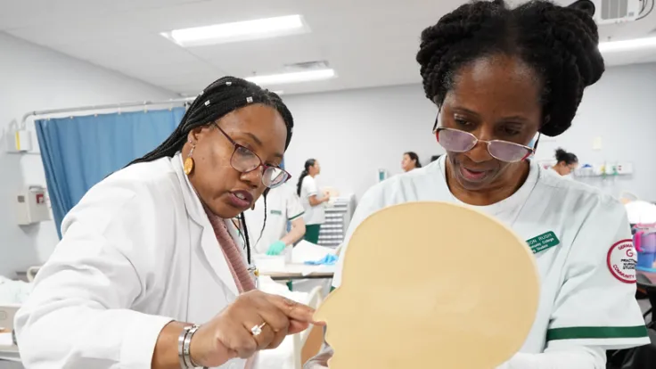 A nursing professor demonstrates a procedure to a student using a model