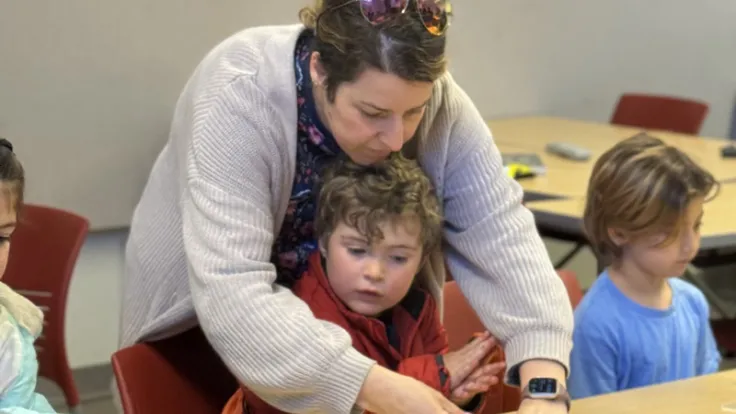 A daycare worker helps a child building a model