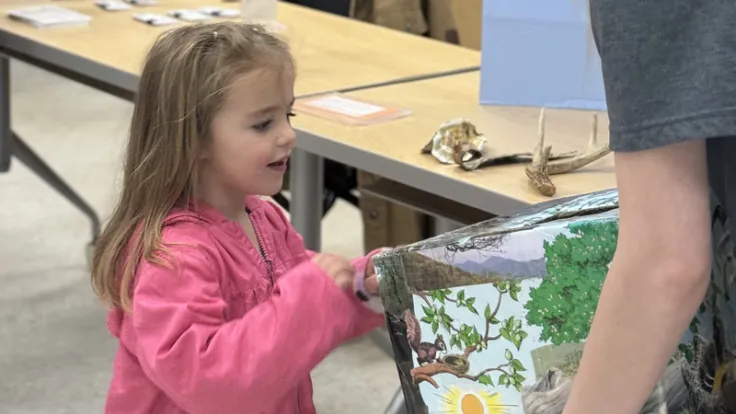 A young child looks inside a toybox in a daycare center