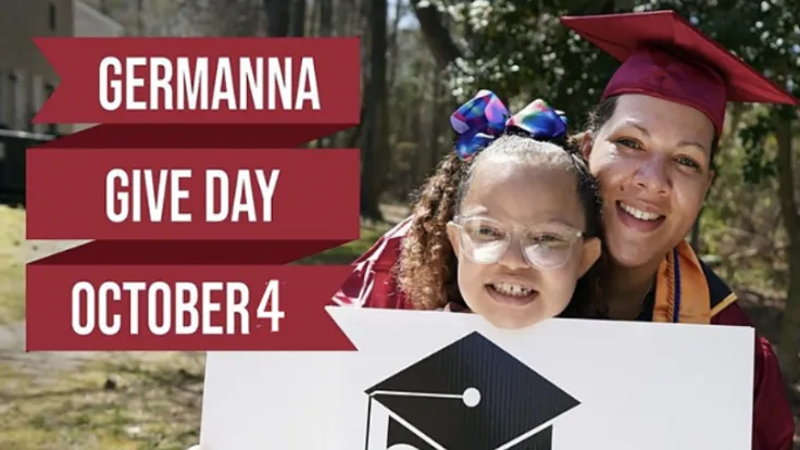 A female graduate wearing a commencement cap and gown, with her young daughter, outdoors. The woman and girl are holding up a placard featuring a drawing of a graduation cap. Overlaid text reads "Germanna Give Day October 4"