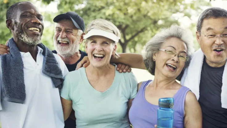 Five older people in workout clothes pose for a photo together