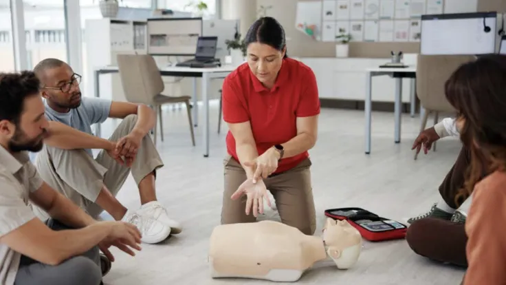 An instructor demonstrates hands-only CPR techniques on a dummy