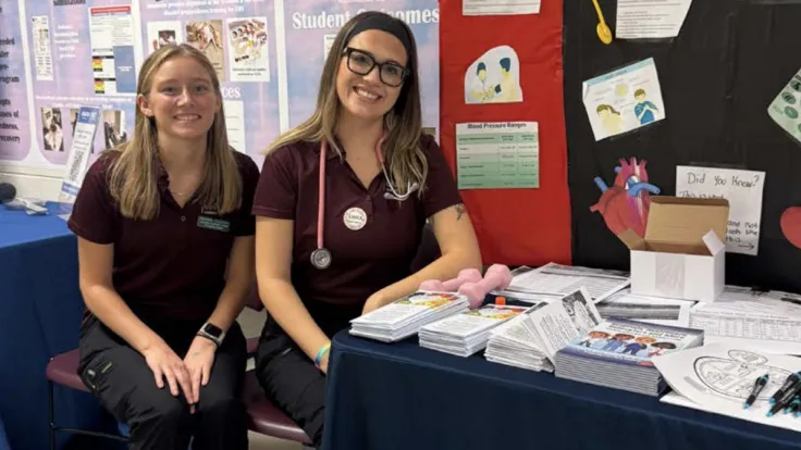 Two Germanna Health Sciences students greet attendees at an open house table