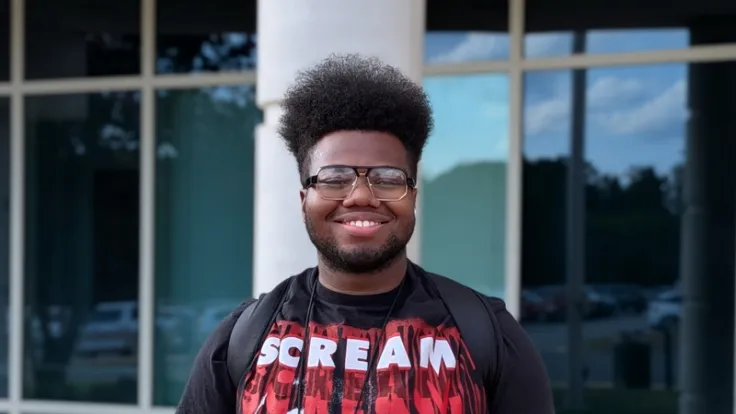 Jerry Perrin smiles for the camera in front of a Germanna building on campus